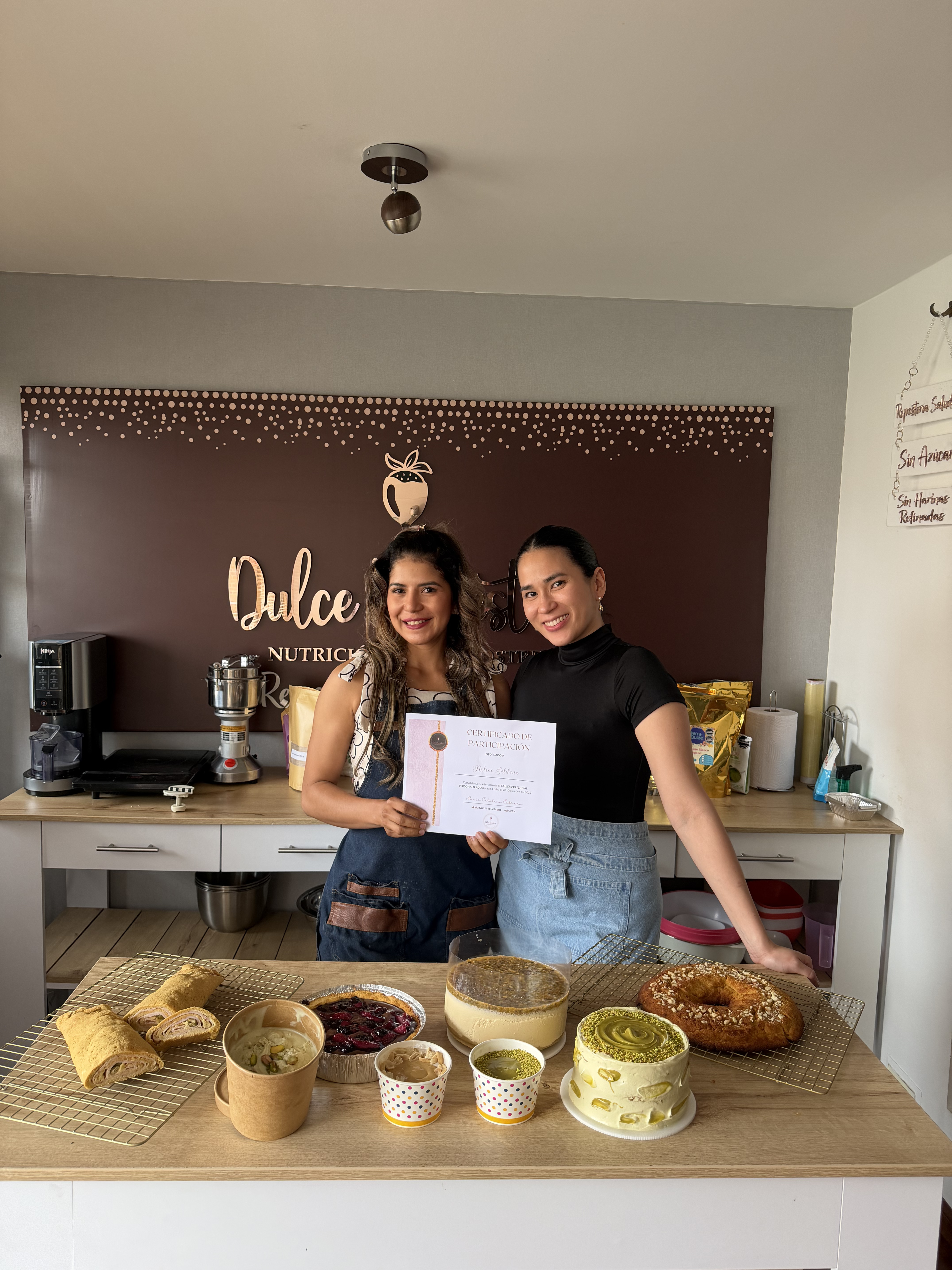Alumnas celebrando con certificado y mesa de postres